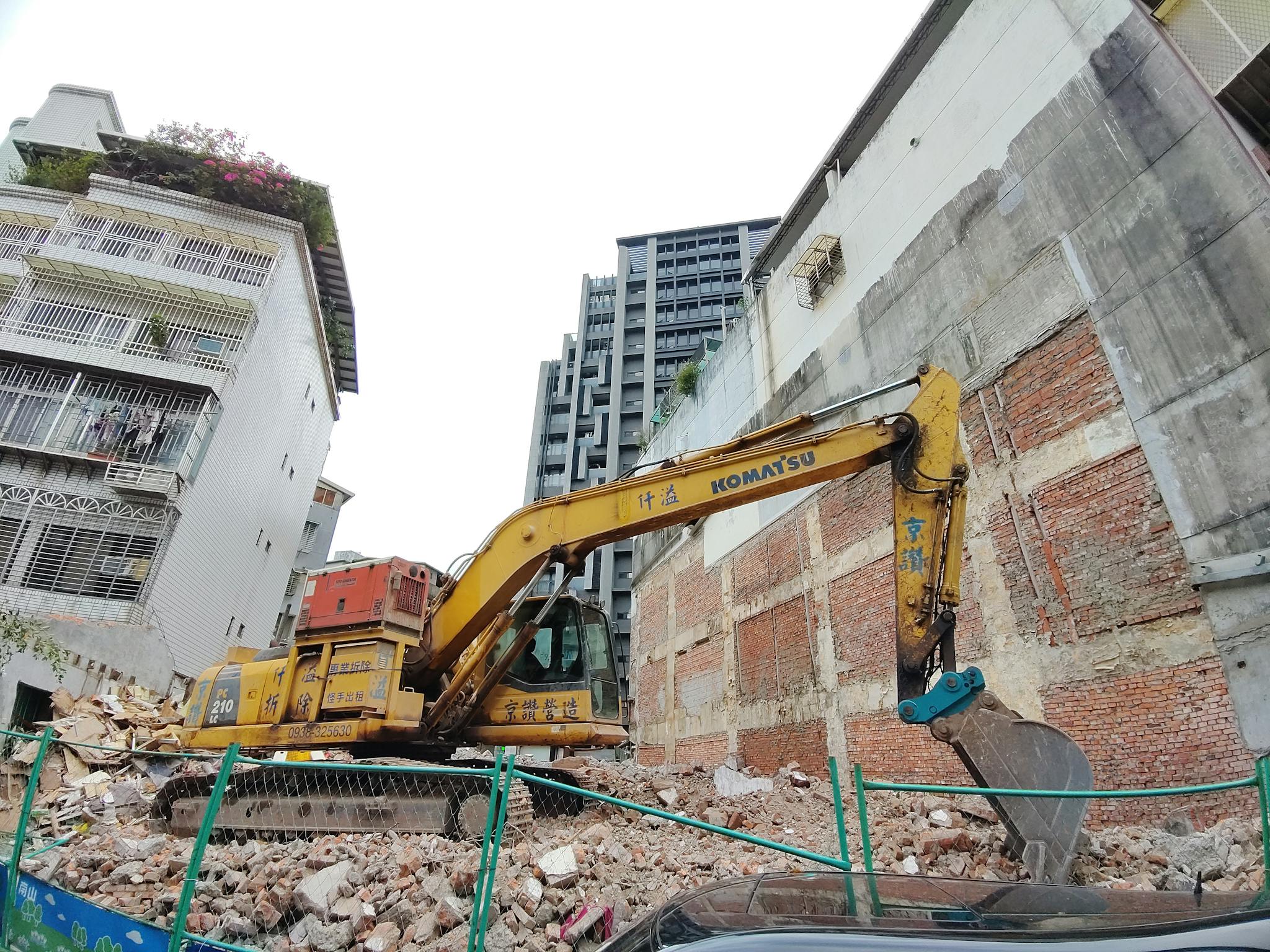 Yellow and Black Excavator Near the White Concrete Building